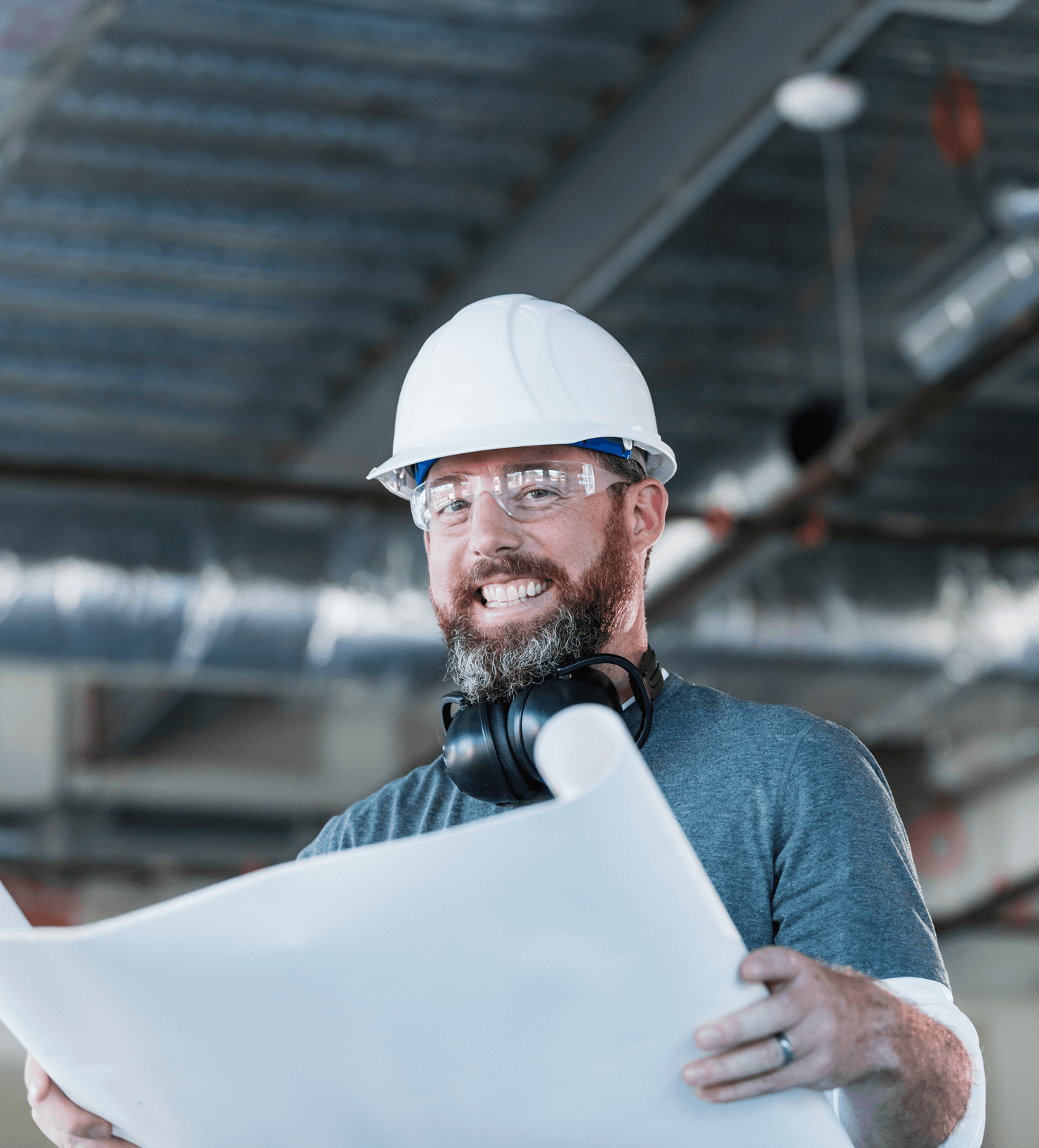 A man wearing white safety helmet while smiling. He is holding an open project plan.
